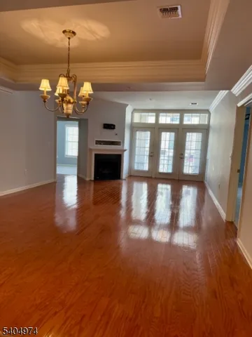 a view of a room with wooden floor chandelier and windows