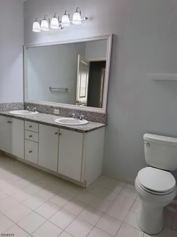 a bathroom with a granite countertop toilet sink and mirror