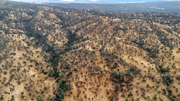 an aerial view of house with yard and mountain view in back