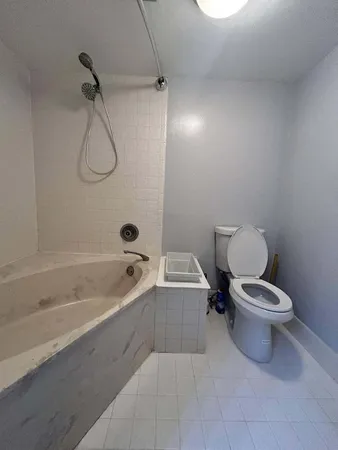 a white toilet sitting next to a bath tub and a shower
