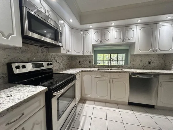 a kitchen with stainless steel appliances granite countertop a sink a stove a microwave and cabinets