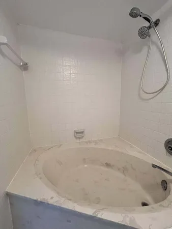 a white bath tub sitting next to a white sink and a shower
