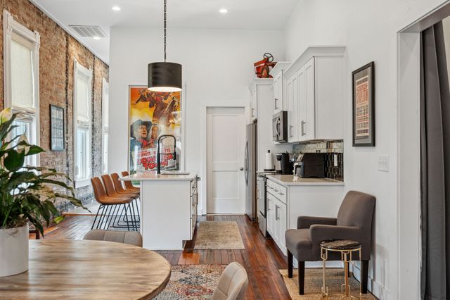 a kitchen with stainless steel appliances granite countertop a refrigerator a stove a sink dishwasher a dining table and chairs with wooden floor