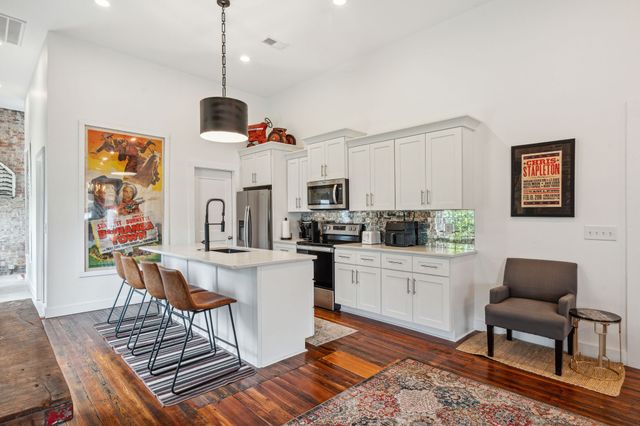 a kitchen with stainless steel appliances kitchen island granite countertop a stove a sink and white cabinets with wooden floor