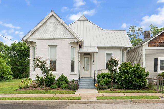 a front view of a house with a yard and potted plants