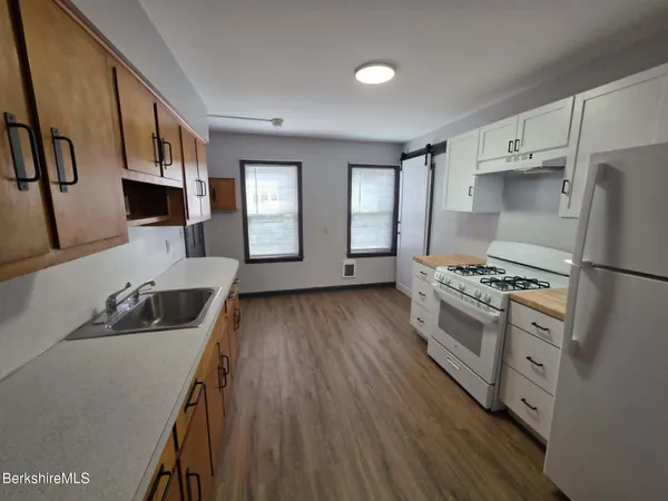 a kitchen with stainless steel appliances granite countertop a refrigerator a stove and a wooden floors