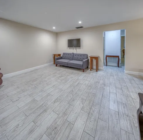 a kitchen with kitchen island a stove a refrigerator a sink a dining table and chairs with wooden floor