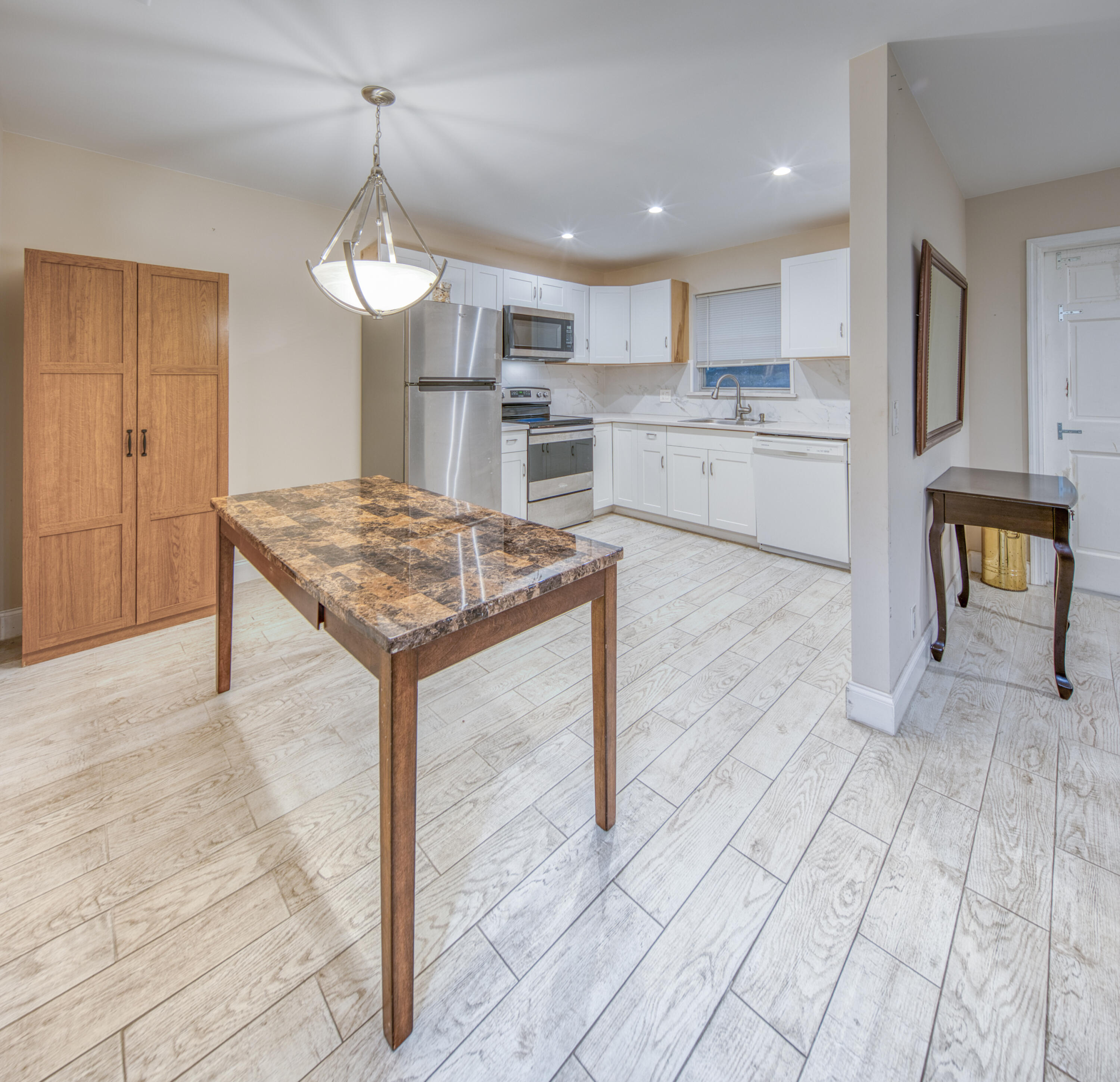 301 South Lakeside Drive, Unit 7 Lake Worth Beach, FL 33460 - Photo 3 of 15 a kitchen with kitchen island a stove a refrigerator a sink a dining table and chairs with wooden floor