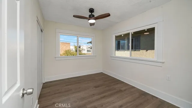 an empty room with wooden floor ceiling fan and windows