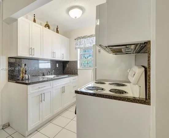 a kitchen with granite countertop white cabinets and white appliances