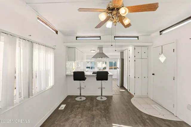 a view of a big room with wooden floor windows and chandelier fan