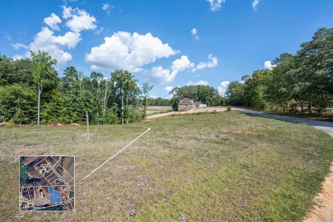 106 C-4-112A Anderson, SC 29625 - Photo 17 of 20 This expansive lot offers ample space for building, bordered by mature trees under a bright sky.