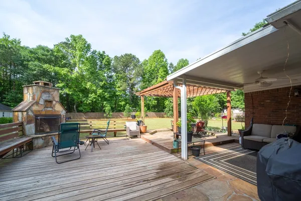 a view of a patio with couches and table and chairs with wooden floor and fence