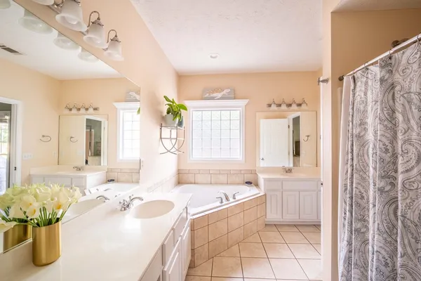 a spacious bathroom with a tub sink and mirror