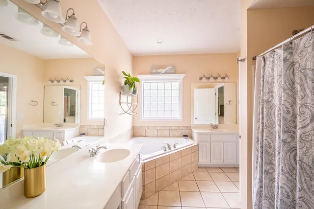 a spacious bathroom with a tub sink and mirror