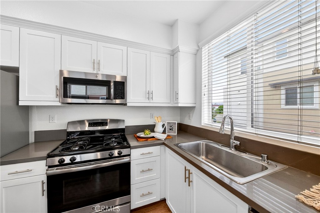 156 North Orange Avenue Brea, CA 92821 - Photo 8 of 44 a kitchen with white cabinets a sink and a stove with wooden floor