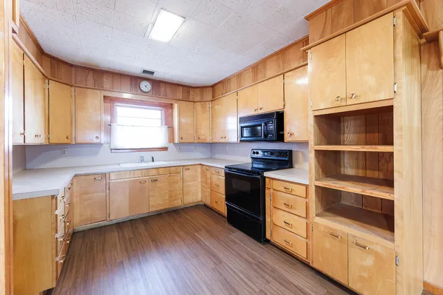 a kitchen with stainless steel appliances granite countertop a stove a sink and white cabinets with wooden floor