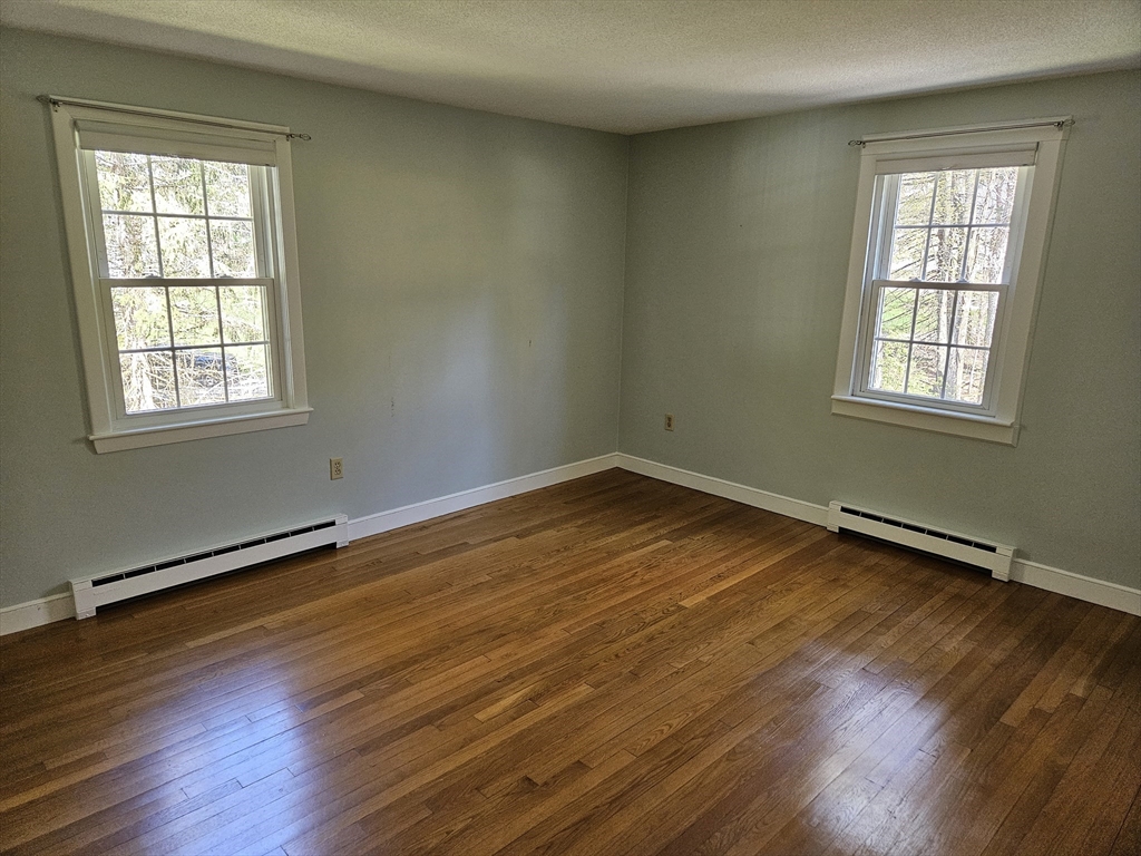 135 Walker Pond Road Sturbridge, MA 01566 - Photo 9 of 16 an empty room with wooden floor and windows