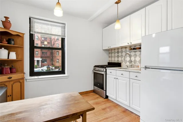 a kitchen with stainless steel appliances granite countertop a refrigerator a stove and white cabinets with wooden floor