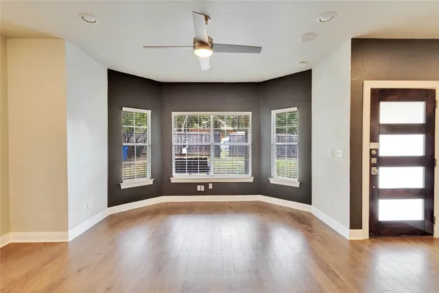 a view of an empty room with a window and wooden floor