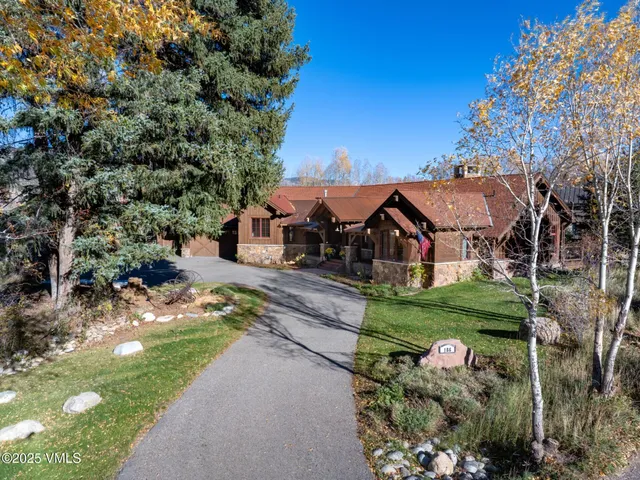 a view of a house with a big yard plants and large trees
