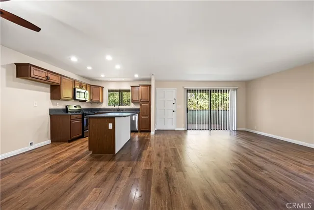 a large kitchen with stainless steel appliances granite countertop a large counter top and wooden floors