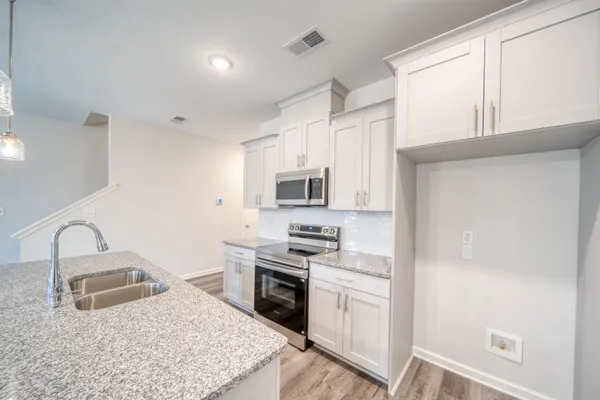 a kitchen with stainless steel appliances granite countertop a stove a microwave and a white cabinets