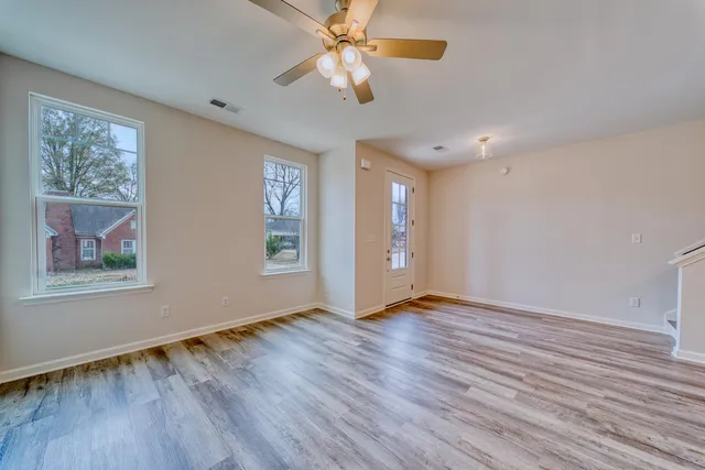 a view of an empty room with window and wooden floor