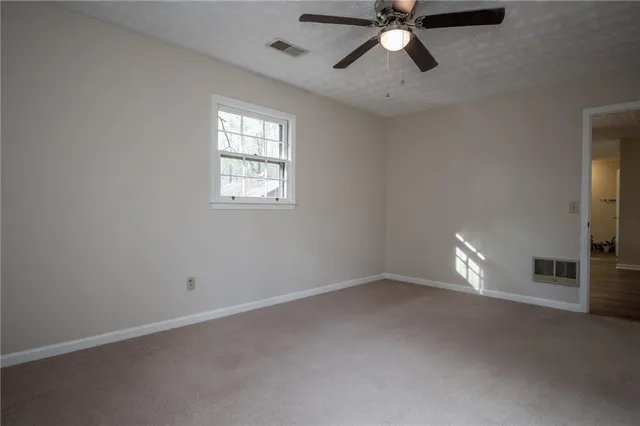 an empty room with a window and a fan
