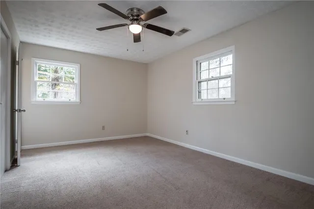 an empty room with a chandelier fan and windows