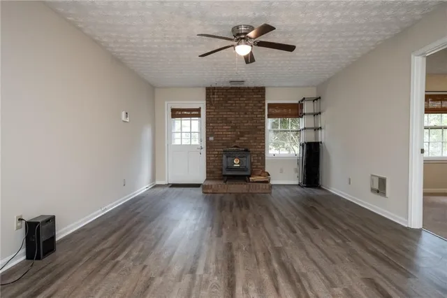 an empty room with wooden floor chandelier fan and windows