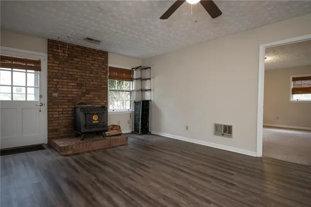 an empty room with wooden floor fireplace and windows