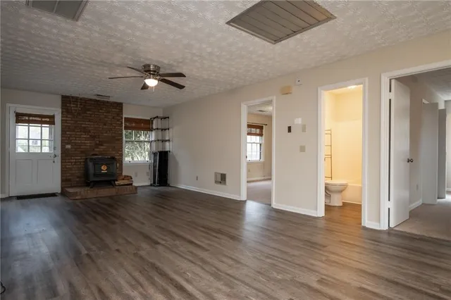 an empty room with wooden floor fireplace and windows