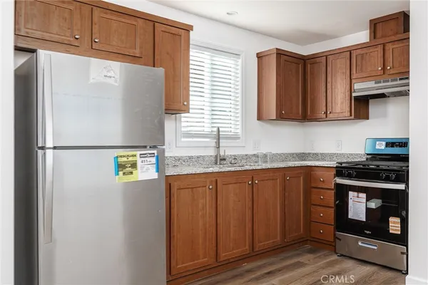 a kitchen with granite countertop a refrigerator stove top oven and sink