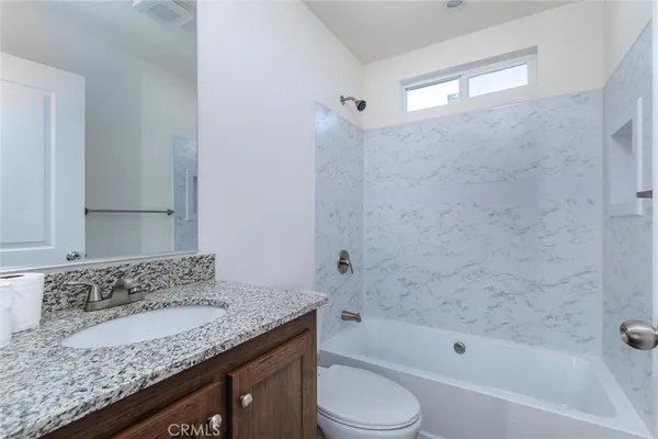 a bathroom with a granite countertop sink a toilet and bathtub