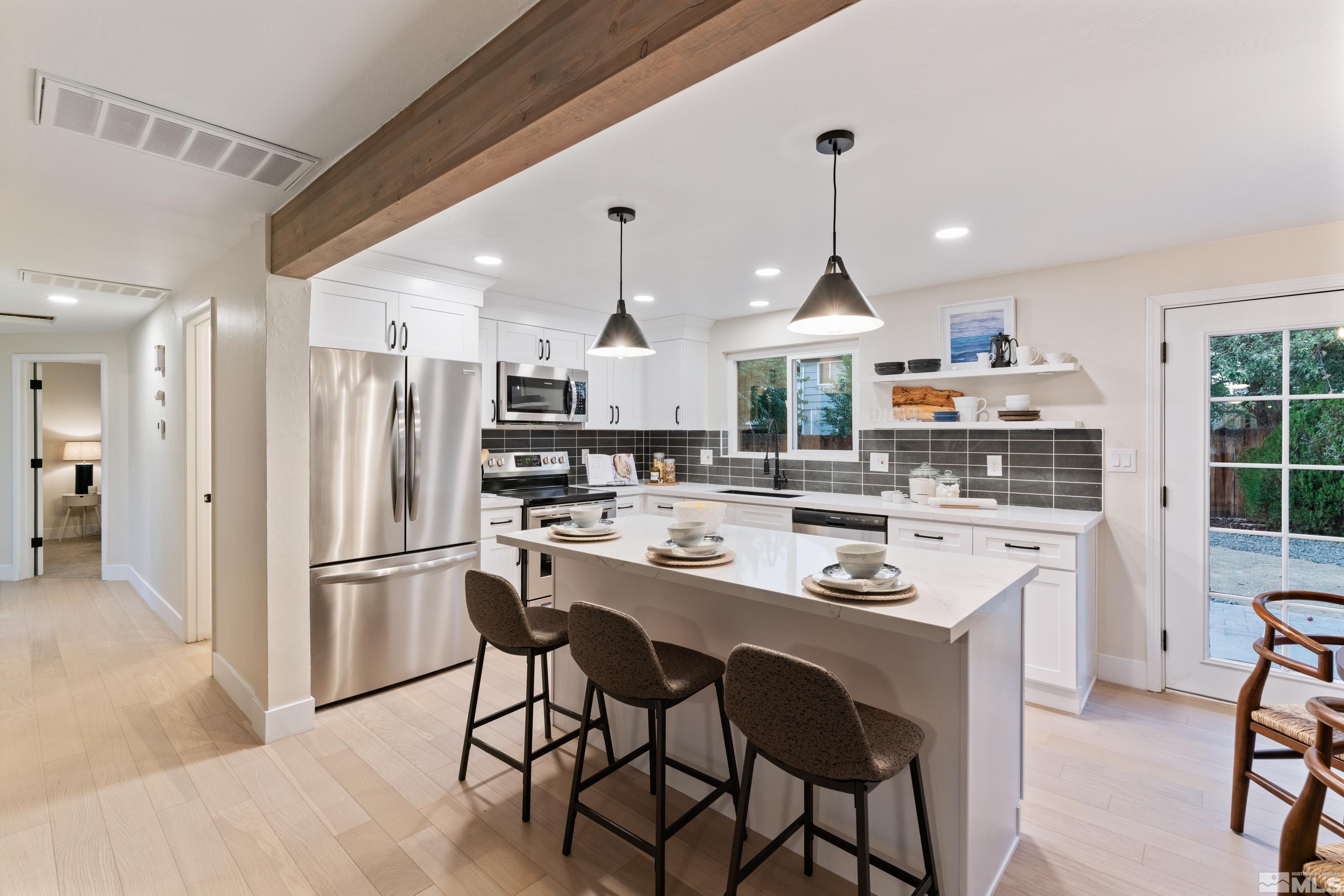 1835 Carlin Street Reno, NV 89503 - Photo 4 of 40 a kitchen with stainless steel appliances a dining table chairs stove and white cabinets