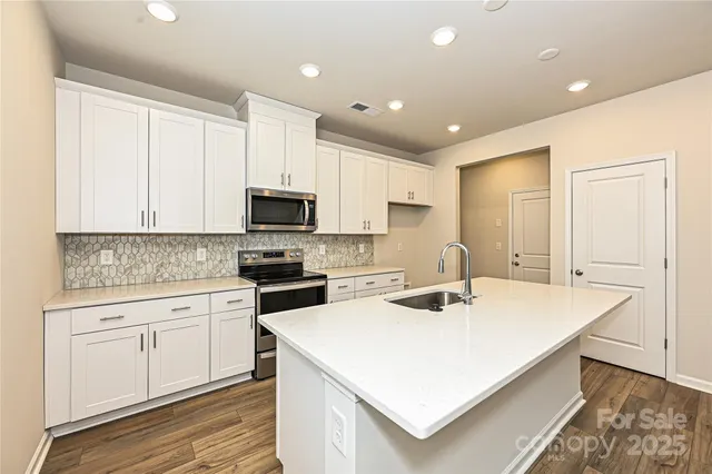 a kitchen with a sink a stove cabinets and wooden floor