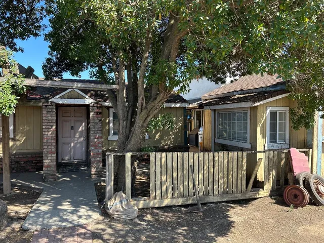a front view of a house with a tree