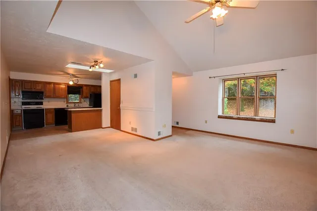 an empty room with chandelier fan and windows