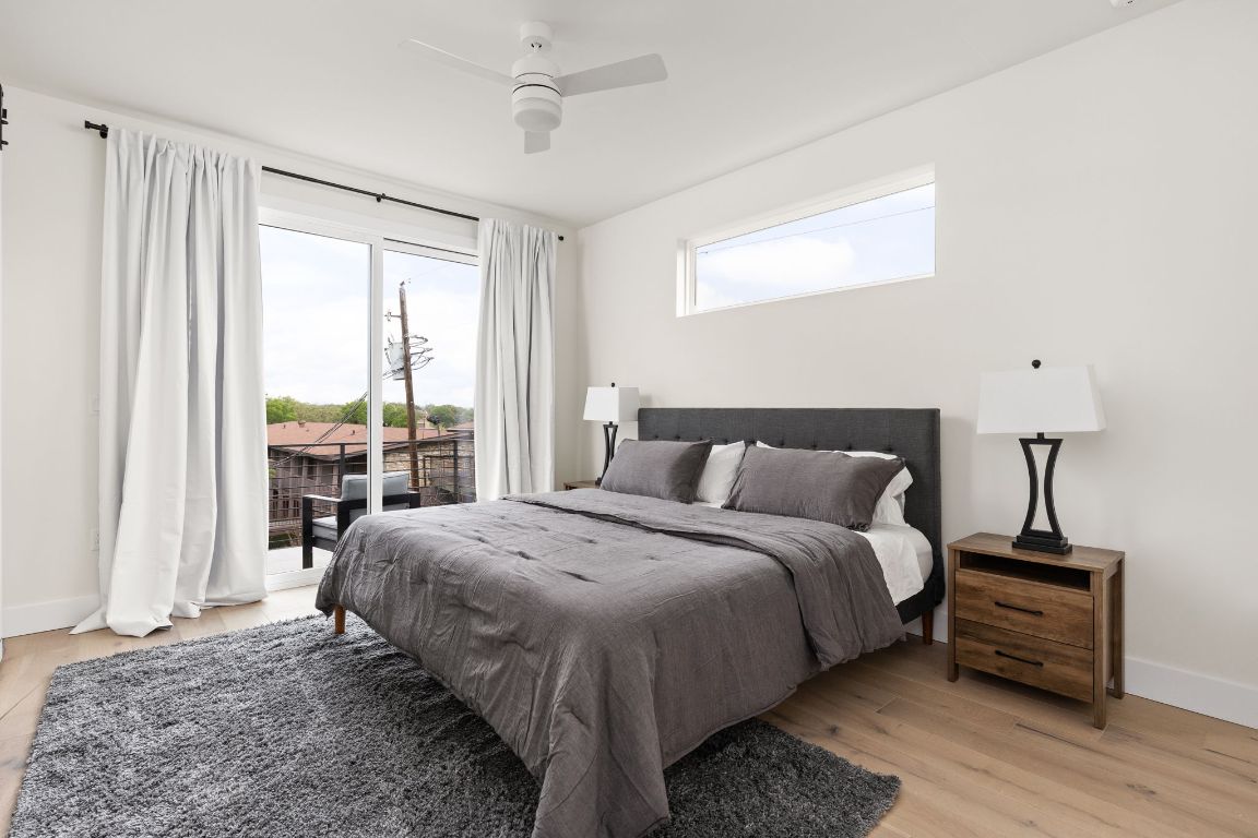 1402 Summit Street, Unit A Austin, TX 78741 - Photo 13 of 30 a bedroom with a bed wooden floor and a lamp