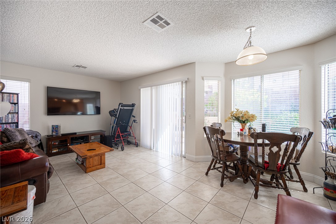 718 Rusty Spur Drive Henderson, NV 89014 - Photo 12 of 50 A well-lit interior space features sleek tile flooring, bay windows, and a sliding glass door.
