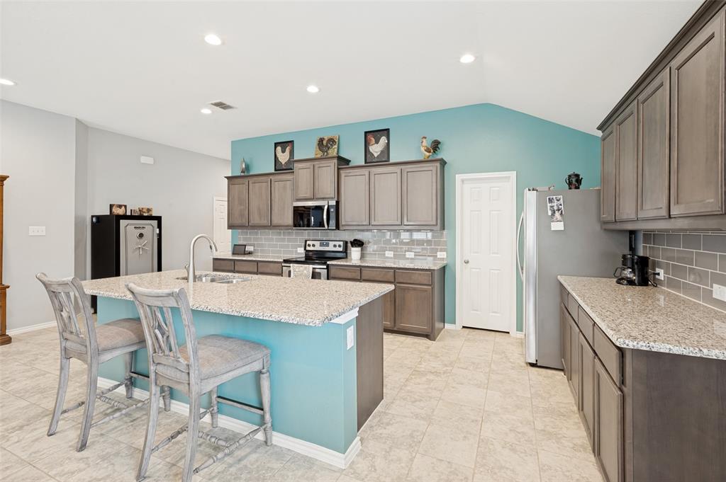 3905 Bridle Path Lane Sanger, TX 76266 - Photo 5 of 26 a kitchen with kitchen island granite countertop a sink cabinets and stainless steel appliances