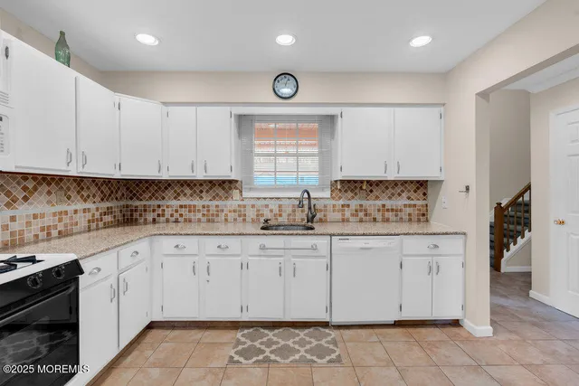 a kitchen with granite countertop white cabinets white appliances with a sink and dishwasher