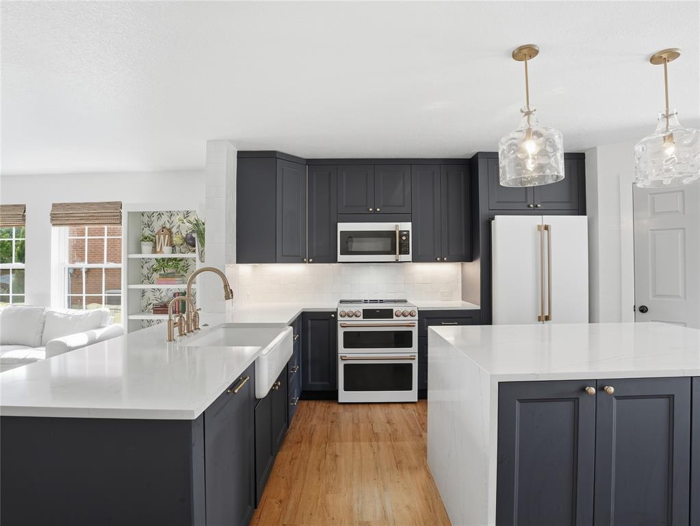 12724 Carpenter Lane Rhome, TX 76078 - Photo 5 of 37 Modern kitchen featuring dark cabinetry, white countertops, wood-finish flooring, a farmhouse sink, and stainless steel appliances