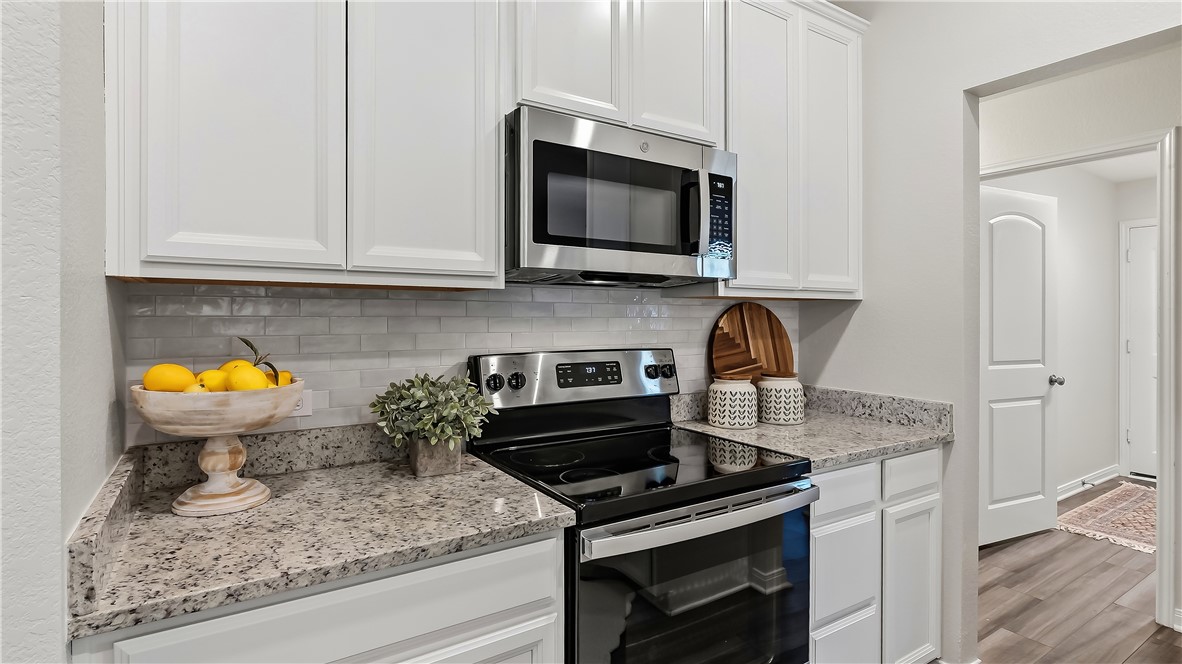2707 Redcap Street Bryan, TX 77803 - Photo 14 of 28 Kitchen featuring white shaker-style cabinetry, stainless steel appliances, granite countertops, and a subway tile backsplash