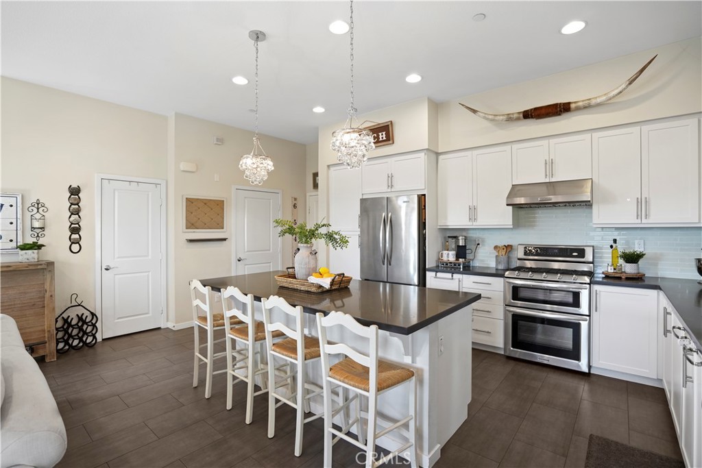 a kitchen with refrigerator a stove a dining table and chairs with wooden floor