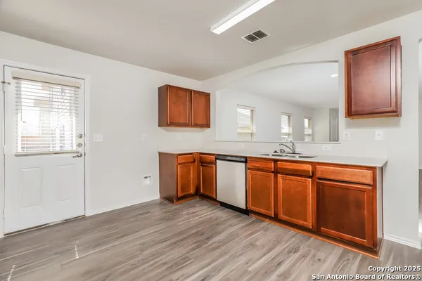 a kitchen with stainless steel appliances granite countertop a sink cabinets and wooden floor