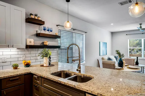 a kitchen with stainless steel appliances granite countertop a sink a stove and a wooden floors