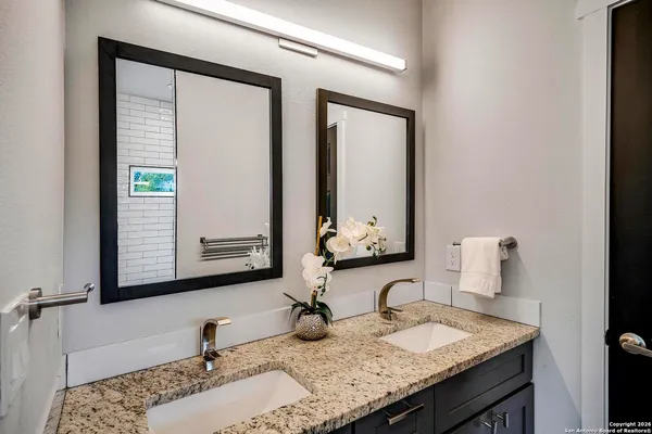 a bathroom with a granite countertop sink and a mirror