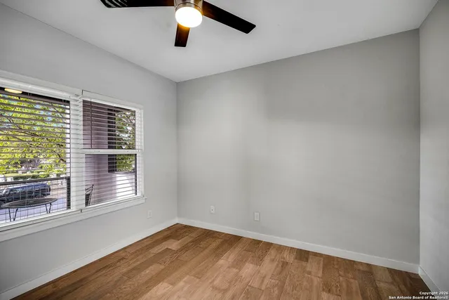 a view of an empty room with wooden floor and a window